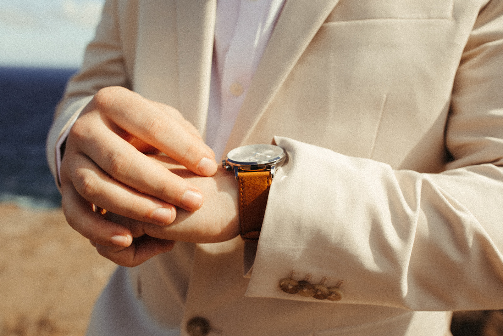groom style, showing off cream colored suit and watch